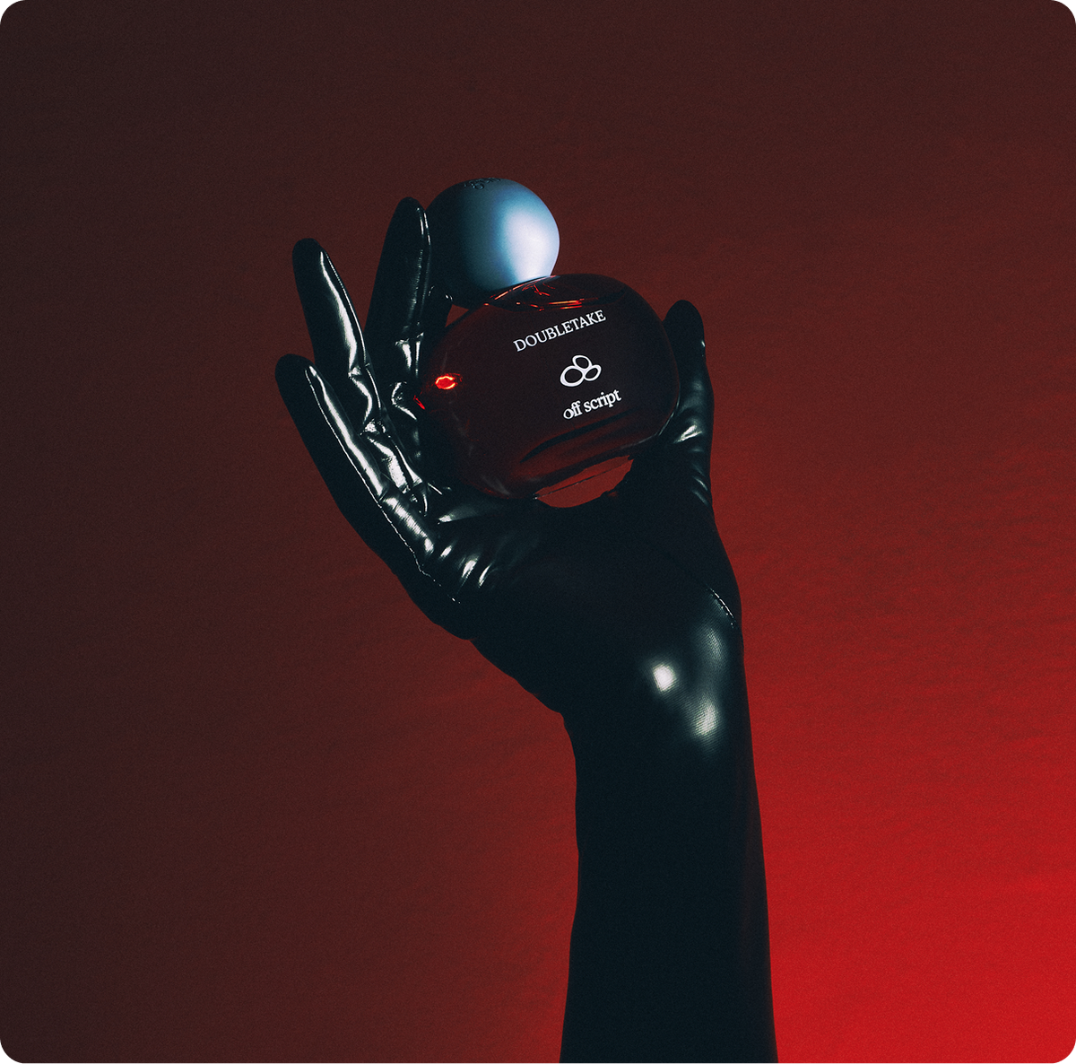 A hand wearing a glossy black glove holds a small oval red perfume bottle with a metallic silver cap against a dark red gradient background. The bottle is labeled 'DOUBLETIME' and 'off to second'.